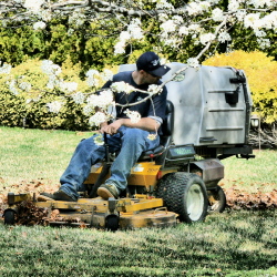 staff performing lawn mowing service on riding lawn mower